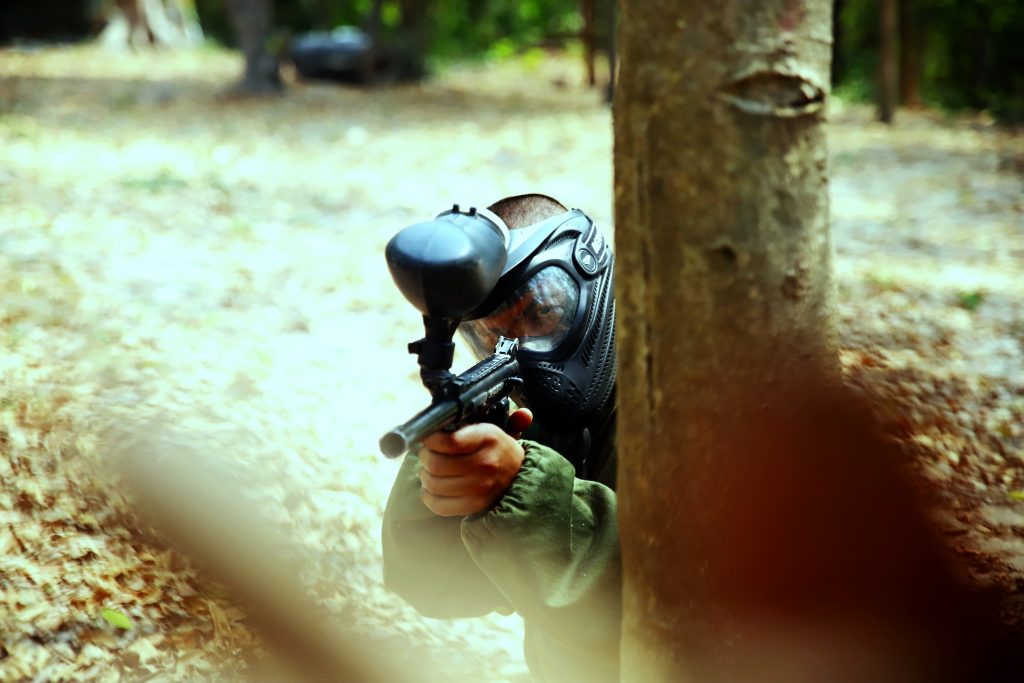 Paintball player behind a tree